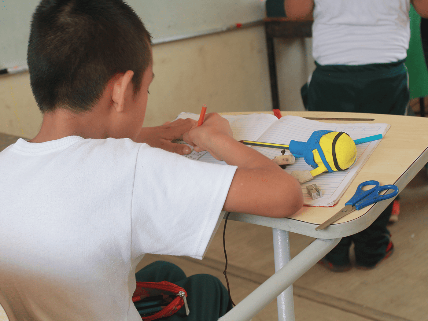 Niño coloreando sobre pupitre escolar Memosa de paleta amplia, adquirido con recursos del Programa La Escuela es Nuestra.