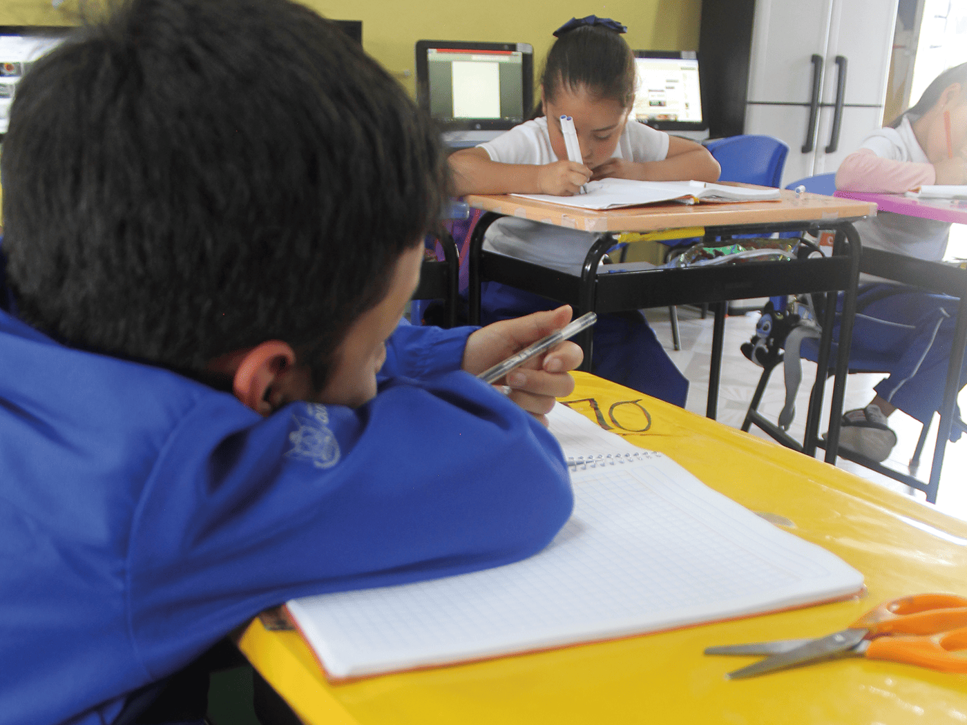 Alumno utilizando mesa escolar y silla Memosa en salón de clases equipado con recursos de La Escuela es Nuestra.